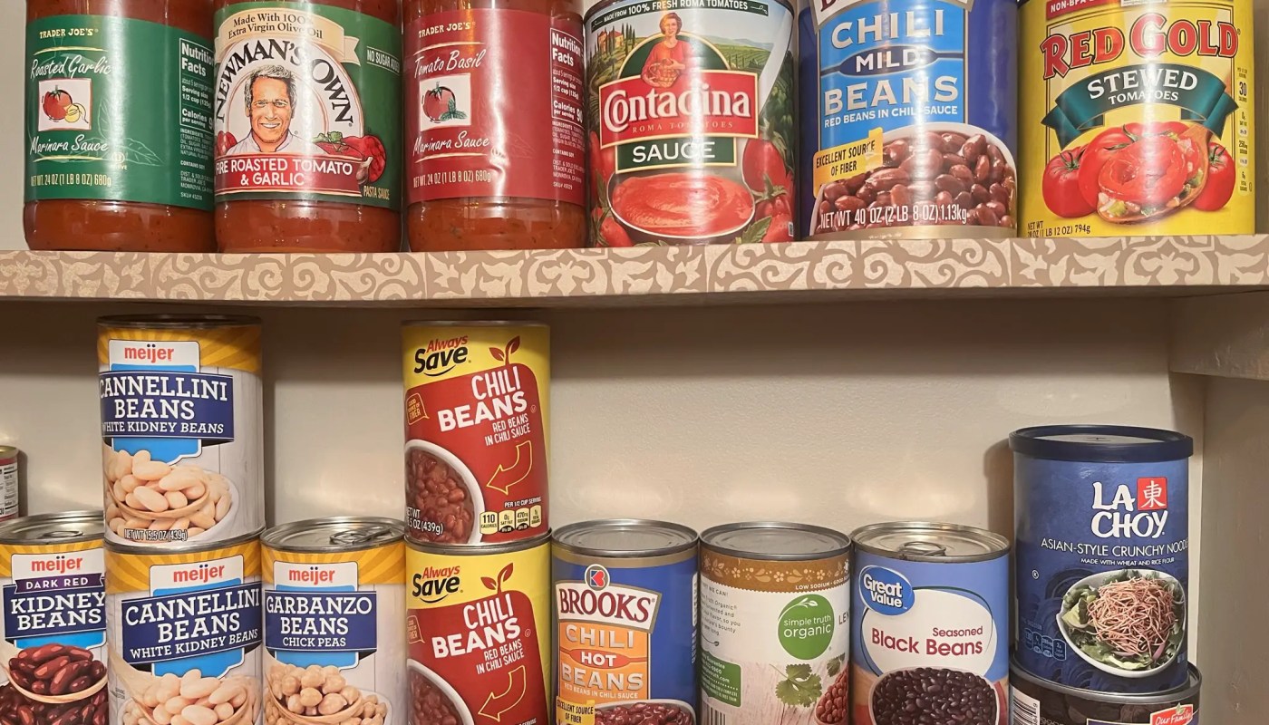 Assorted canned and dry food items in a pantry depicting the concept of understanding the shelf life of stored food.