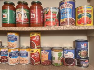 Assorted canned and dry food items in a pantry depicting the concept of understanding the shelf life of stored food.