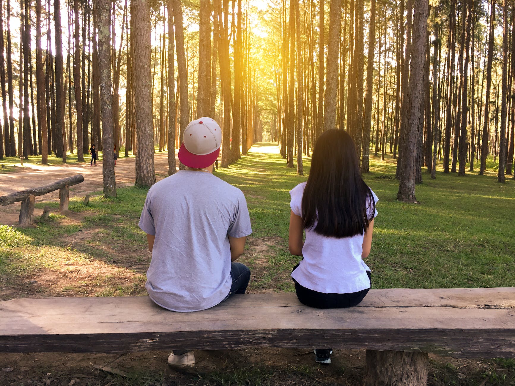 man and woman sitting on bench in woods