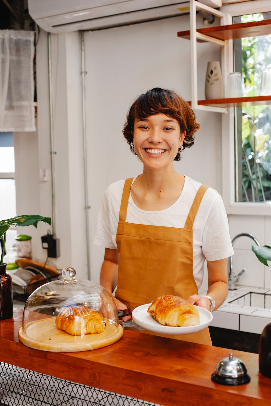 cheerful woman serving croissants in café - Michigan Laws for teens