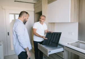 man in white polo showing drawer for kitchen utensils