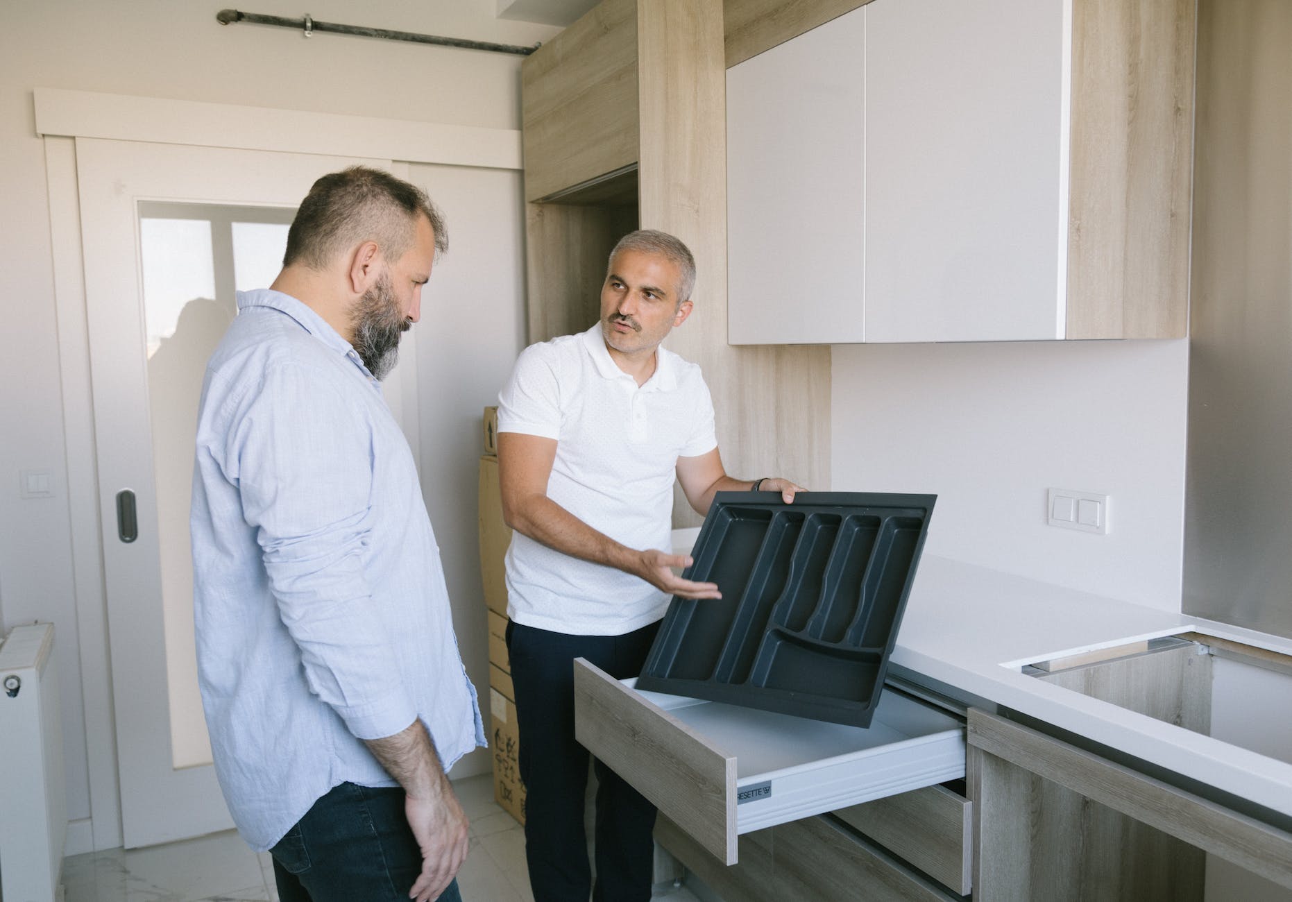 man in white polo showing drawer for kitchen utensils - Michigan rental tips