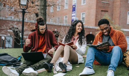 cheerful multiethnic students with books sitting near university - Featured image of diverse students at one of the best colleges in Michigan