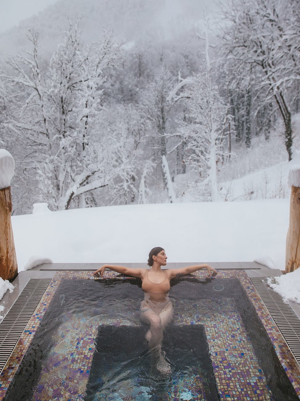 woman in a hot tub near a snow covered forest