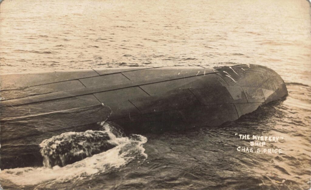 Capsized ship partially submerged in water.