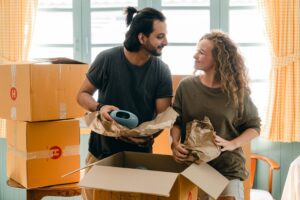 A detailed guide on Michigan moving tips for packing fragile items multiethnic couple packing ceramic belongings in parchment before relocation