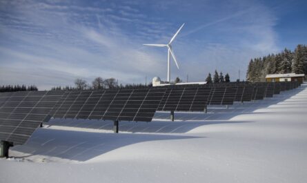 solar panels on snow with windmill under clear day sky