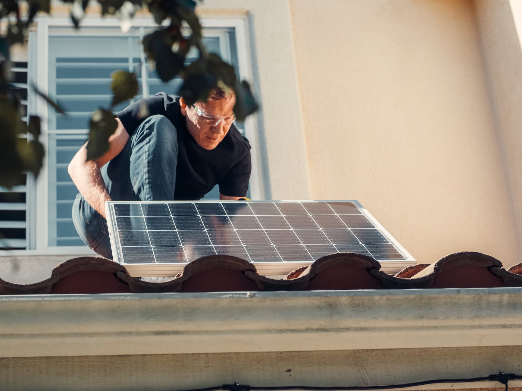 a man in black shirt installing a solar panel on the roof - Michigan solar energy