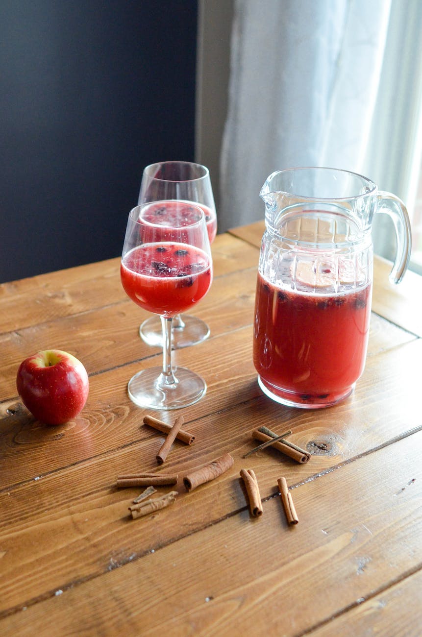 refreshing drink poured into glasses and placed on table with apple and cinnamon sticks