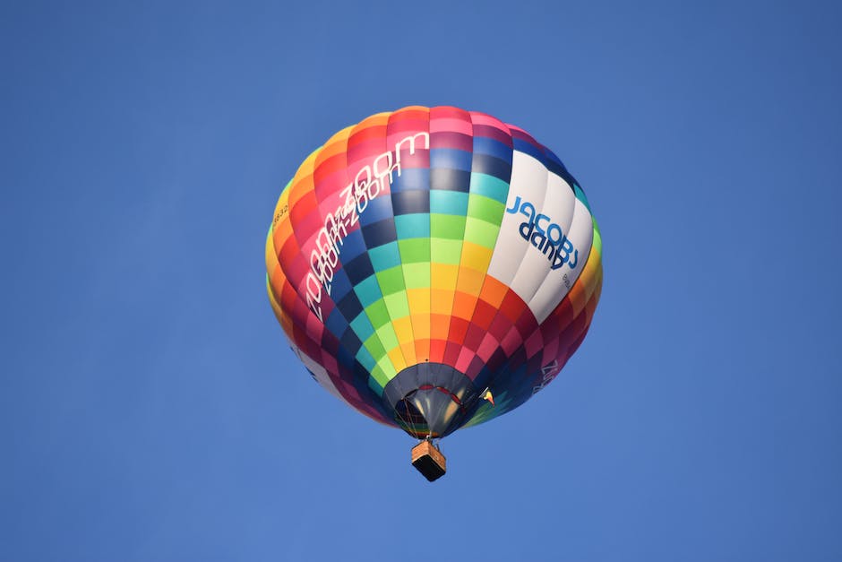 A colorful hot air balloon festival with balloons in the air and people watching from the ground.