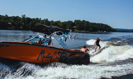 anonymous athlete on wake board near motor boat on lake