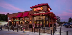 a brick restaurant with a fence and a gate - Sheetz Michigan