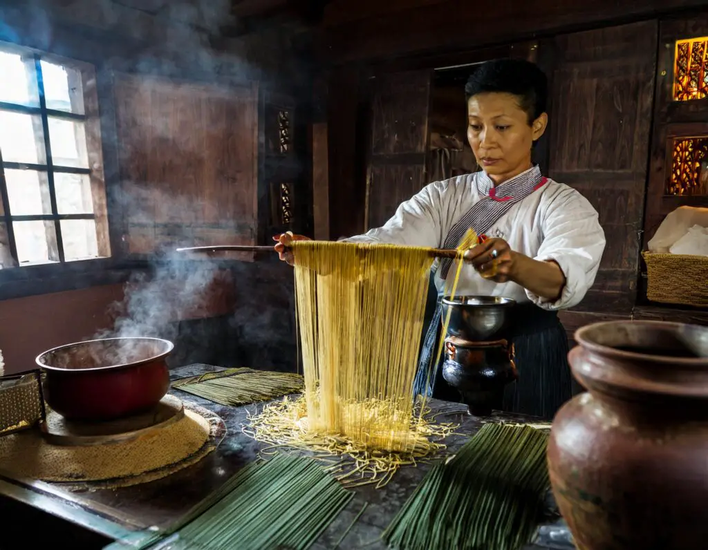 a woman holding a long spaghetti over a table