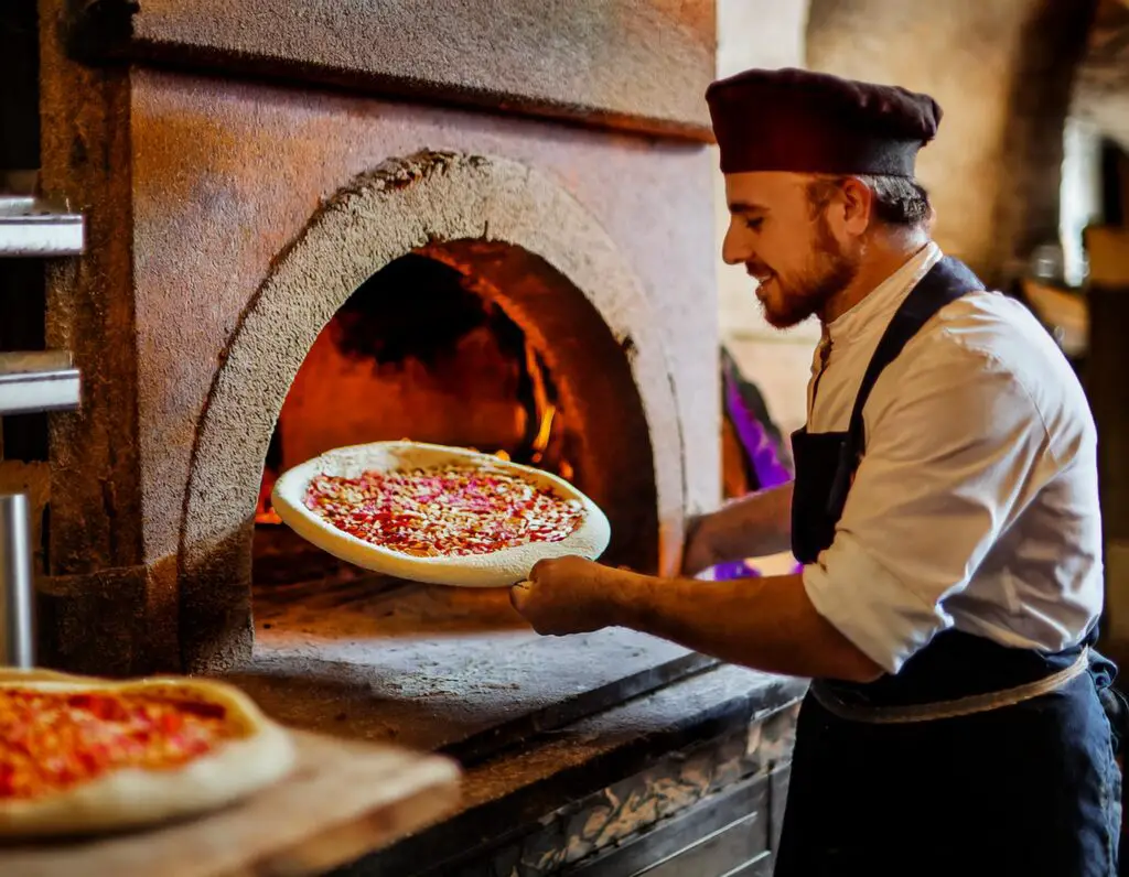 a man holding a pizza in a oven