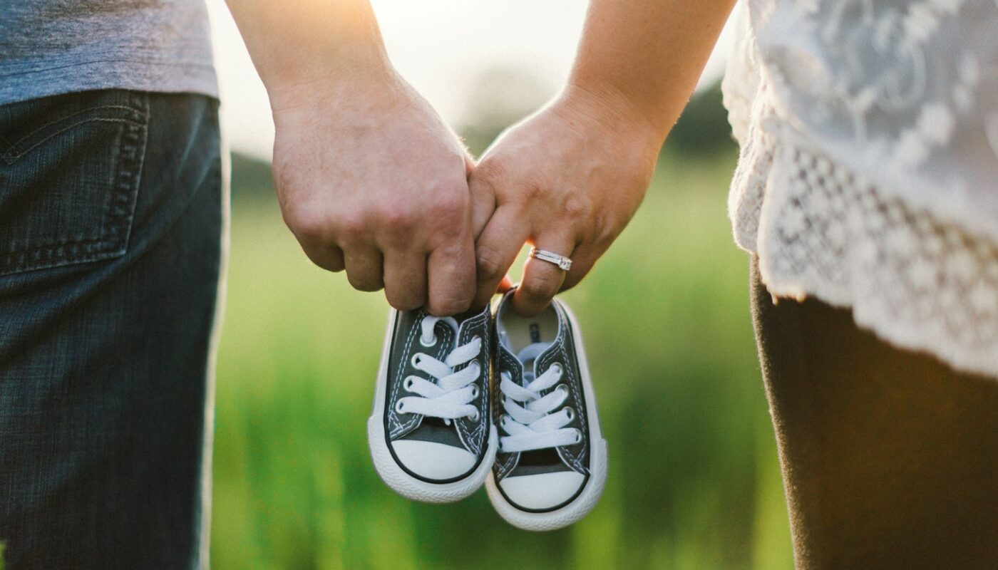 a man and woman holding baby shoes