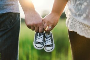 a man and woman holding baby shoes