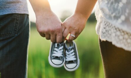 a man and woman holding baby shoes