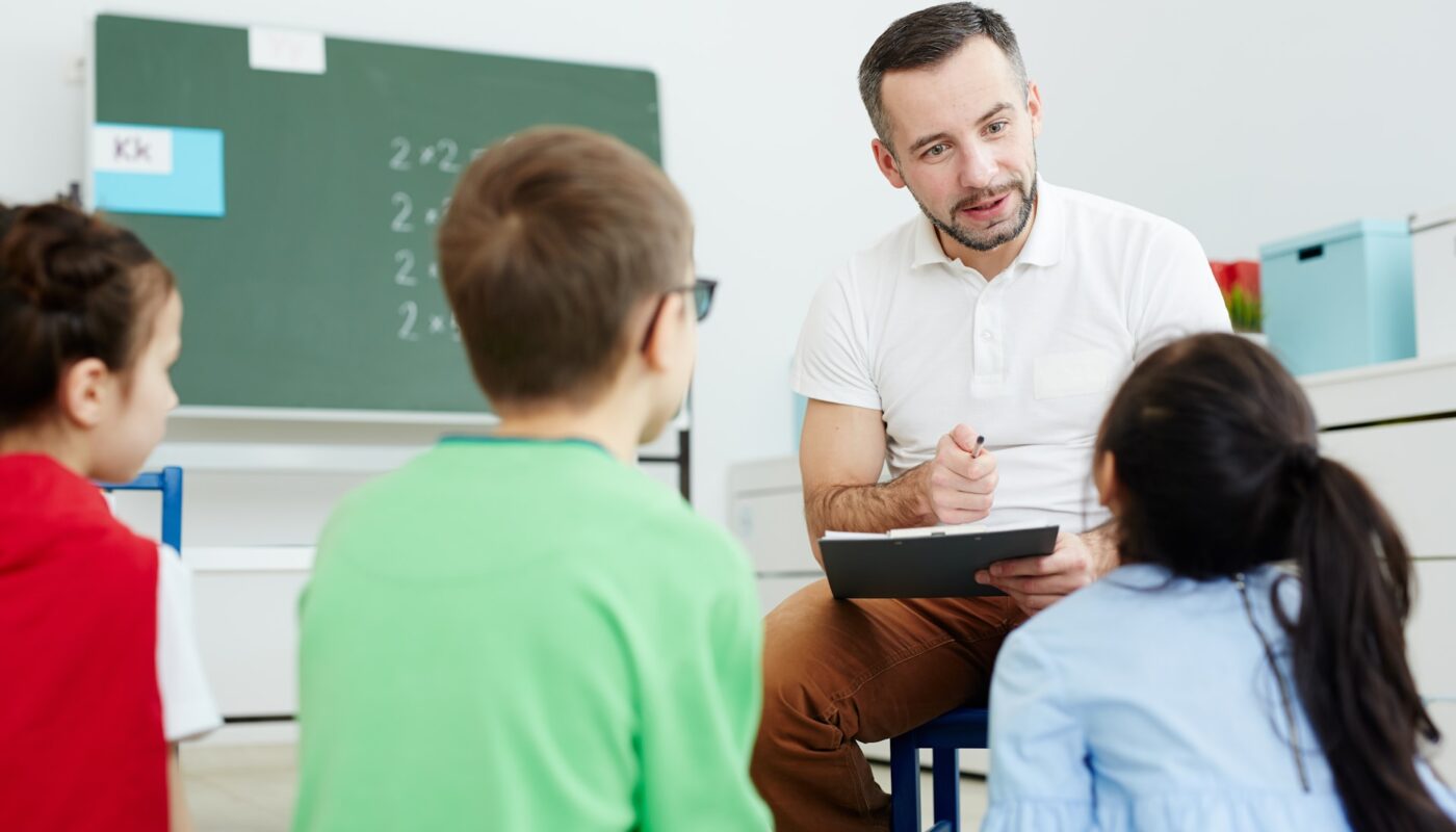 a man sitting in a chair and holding a clipboard with a child in the background