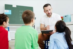 a man sitting in a chair and holding a clipboard with a child in the background