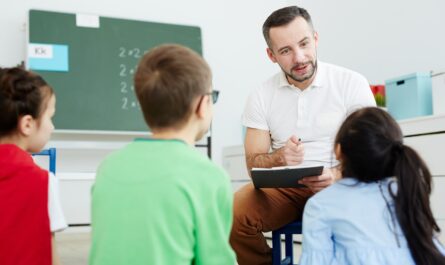 a man sitting in a chair and holding a clipboard with a child in the background