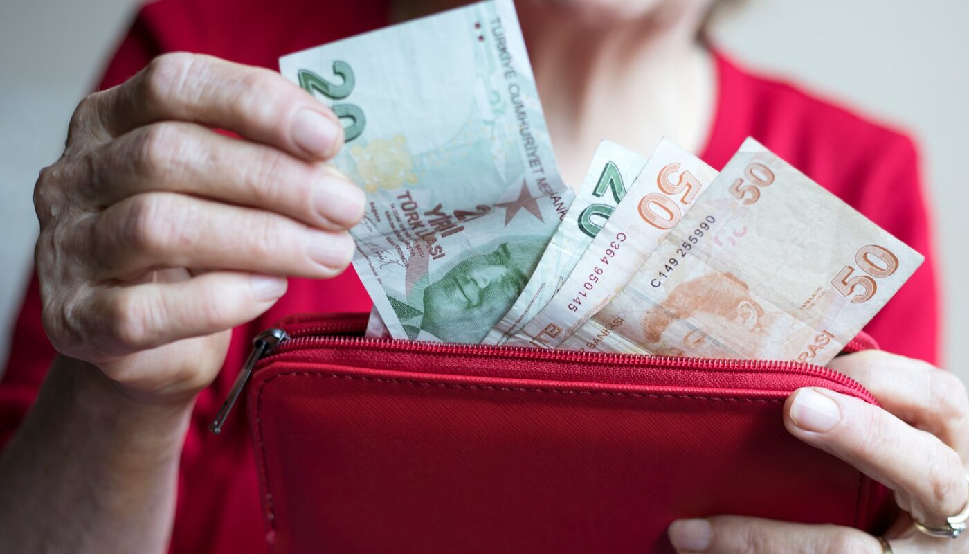 a person holding a red wallet full of money