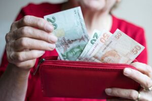 a person holding a red wallet full of money