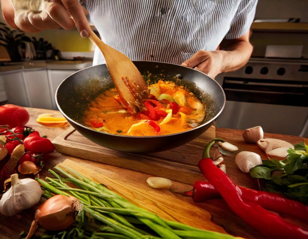 a person cooking thai red curry recipe in a wok