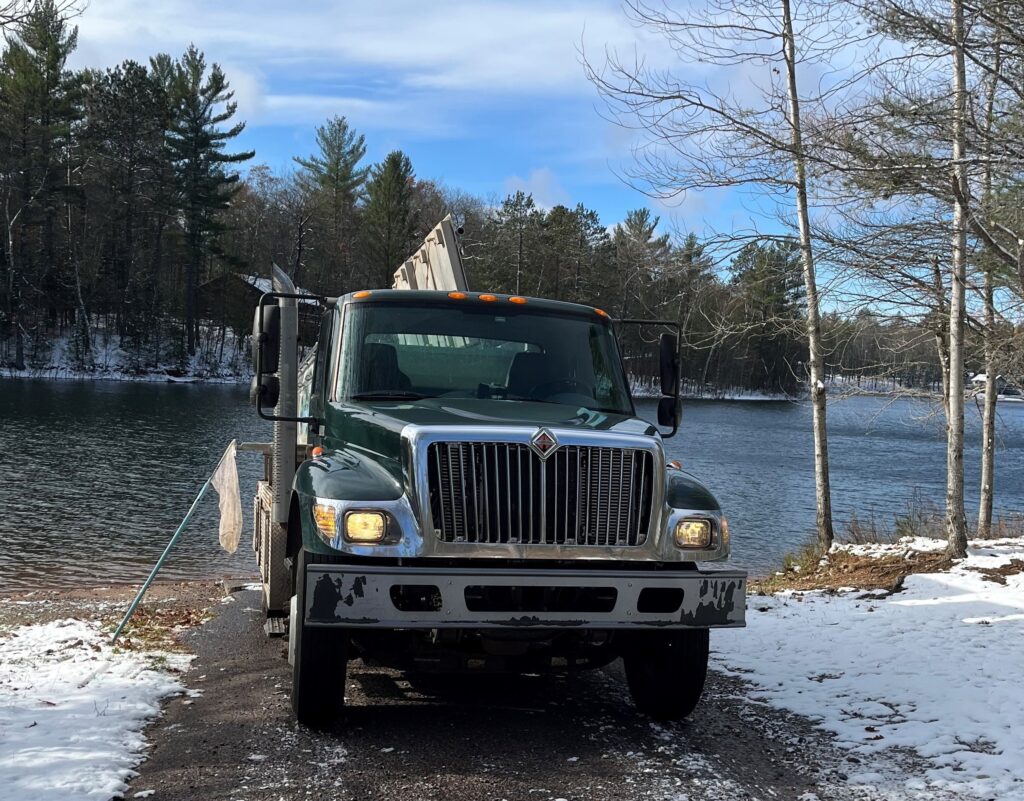 a truck parked on a snowy road next to a body of water