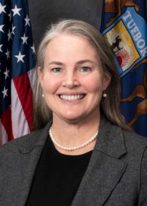 a woman smiling in front of flags