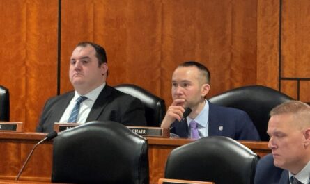 a group of men sitting in a room with microphones