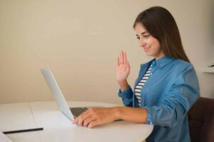 a woman waving at a laptop