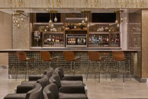 a bar with chairs and a shelf with bottles