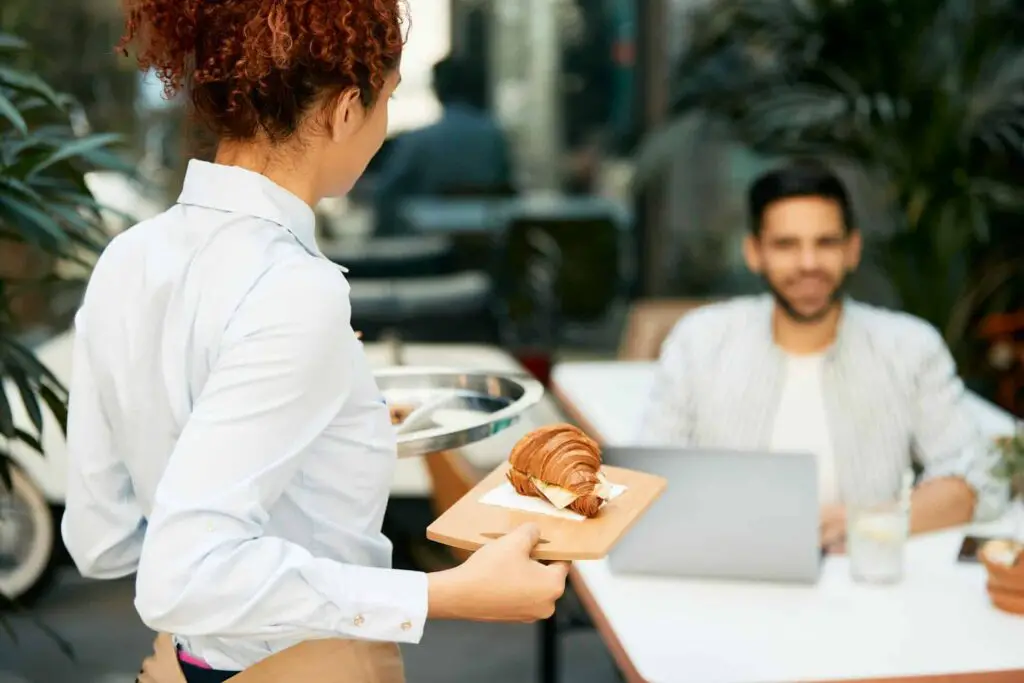 a woman holding a tray with a croissant on it