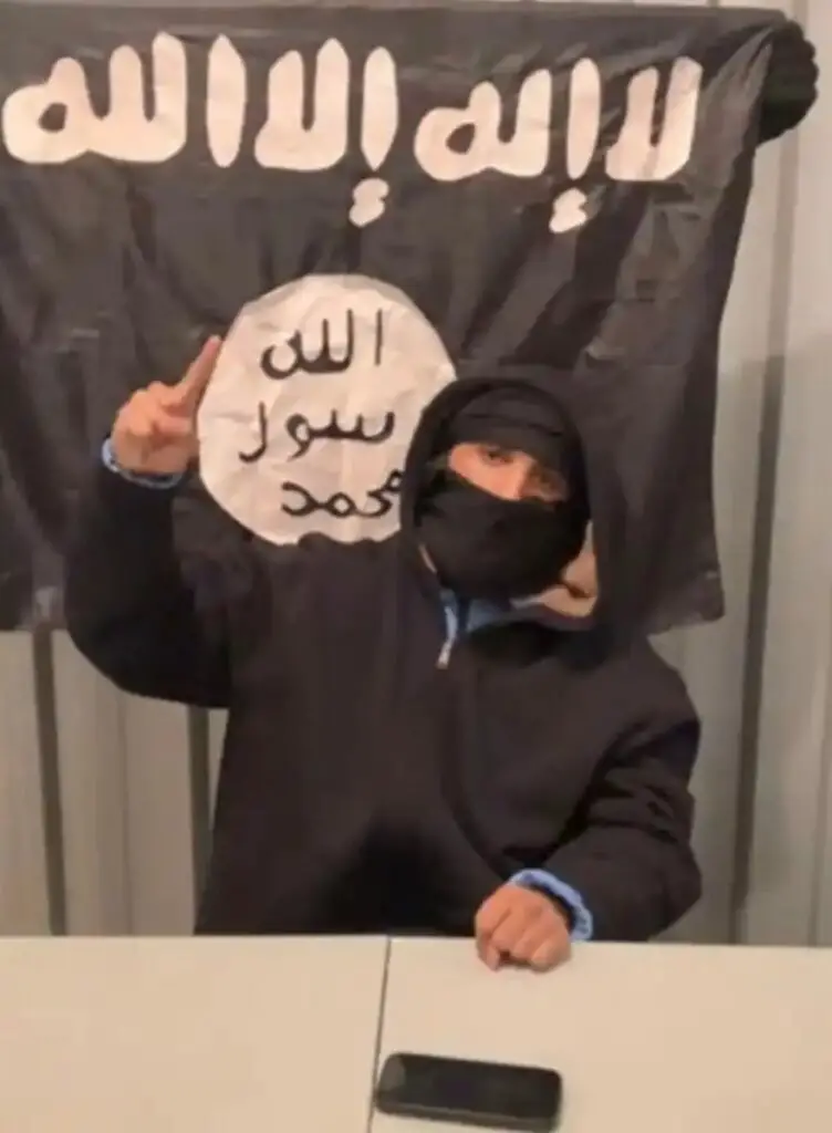 A video still from the federal complaint of Ammar Abdulmajid-Mohamed Said in front of an ISIS flag (Department of Justice)