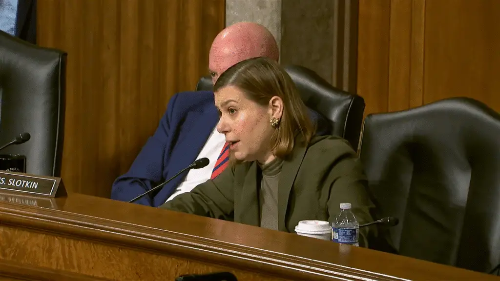 a woman sitting at a podium with a man behind her
