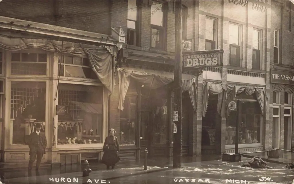 a woman sitting on a sidewalk in front of a store