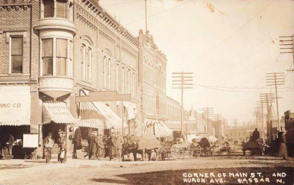 a black and white photo of a street with a horse drawn carriage
