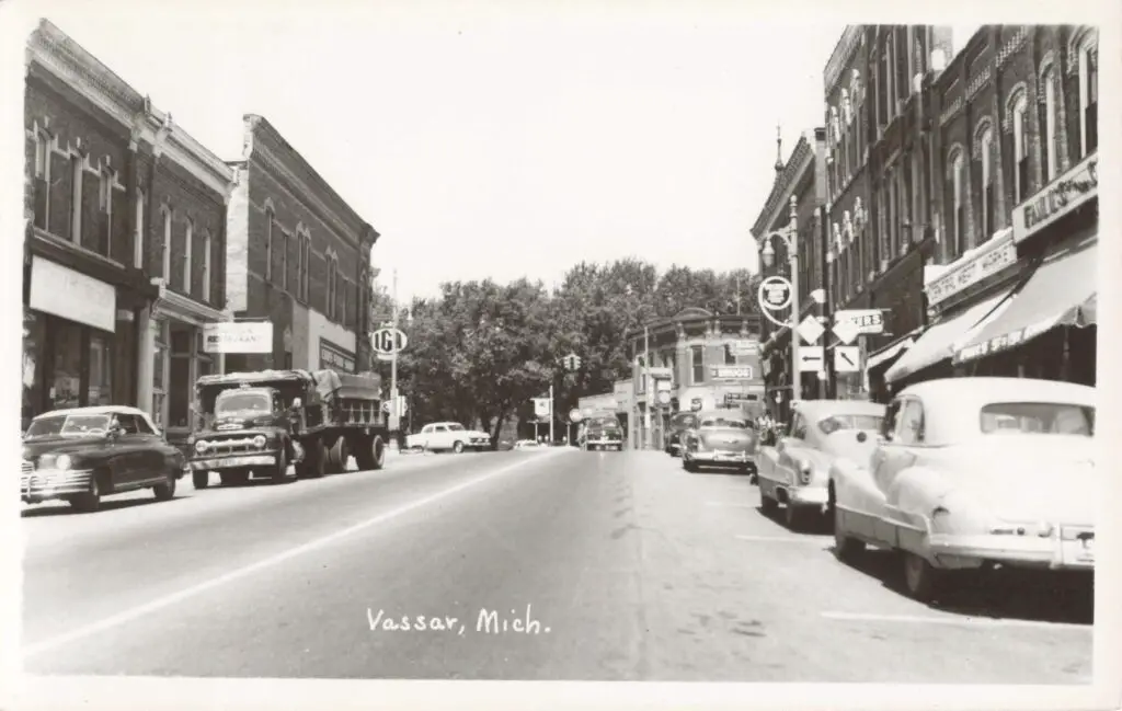 a black and white photo of a street with cars and buildings