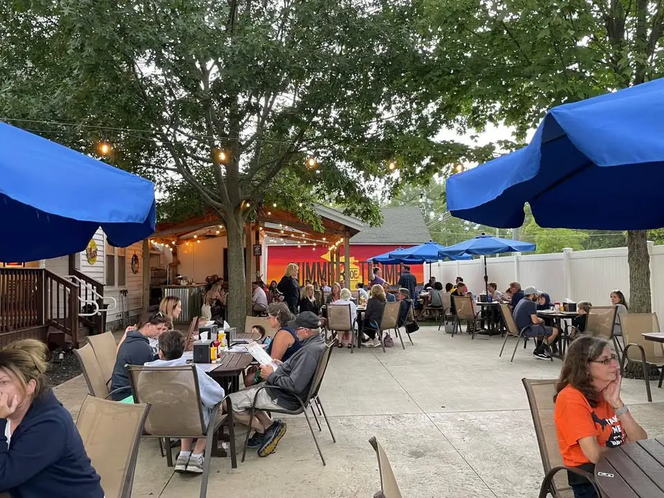 a group of people sitting at tables under blue umbrellas