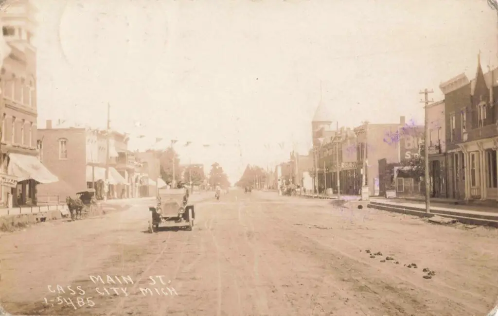 an old photo of a street with a car - history of cass city michigan