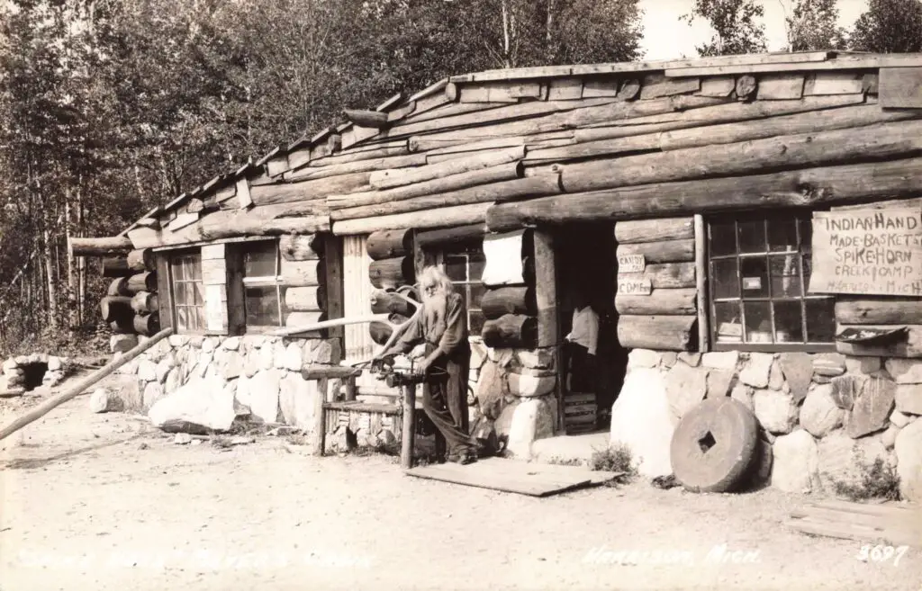 a man holding a sword in front of a log cabin