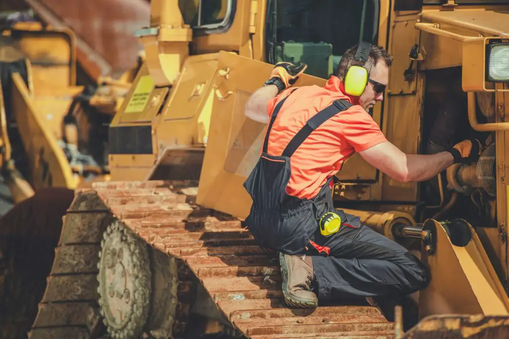 Worker repairing heavy machinery outdoors in the hardest working state.