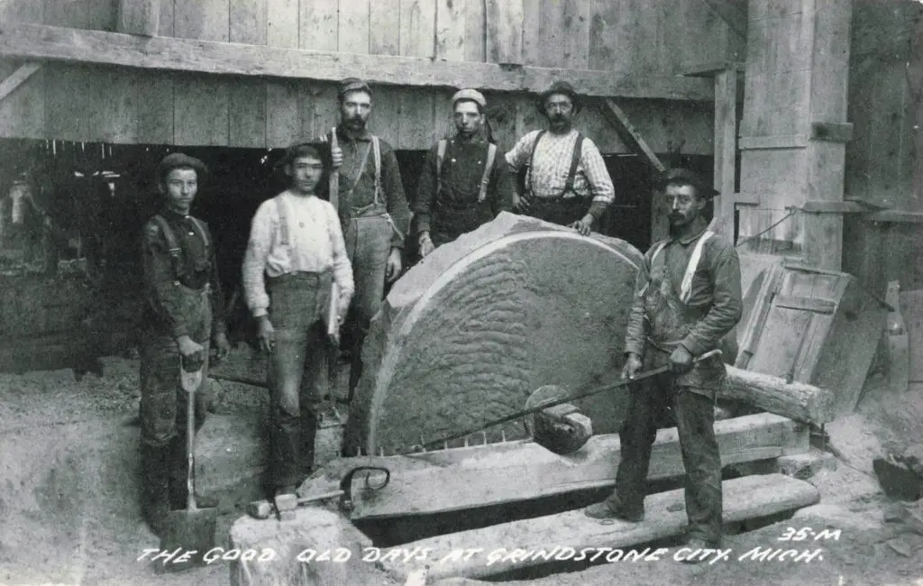 Historical workers with a large grindstone.