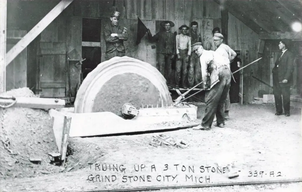 Workers operating a large grinding stone.
