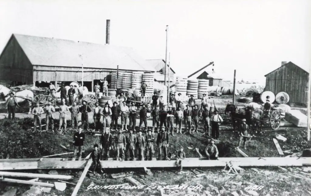 Group of workers near farm buildings.