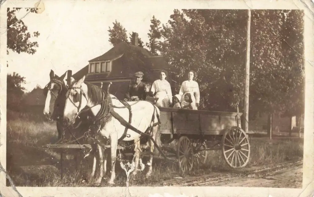 Vintage horse-drawn wagon with people.