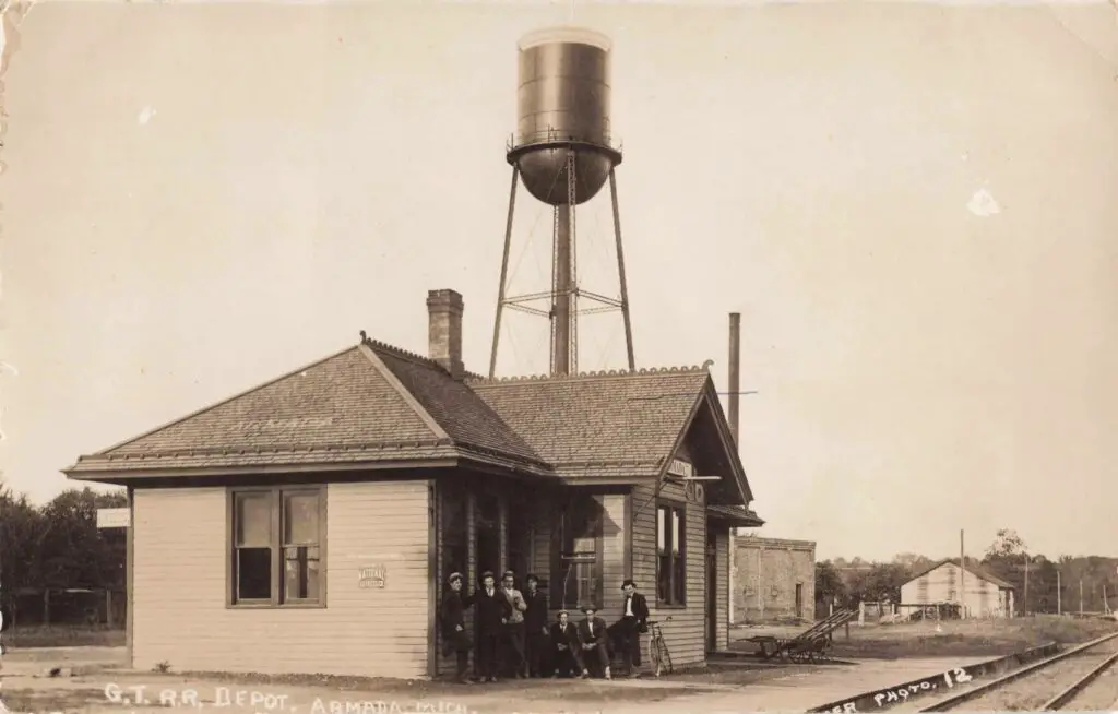 Armada Depot: Frame station on a spring day; baggage cart near the platform.
