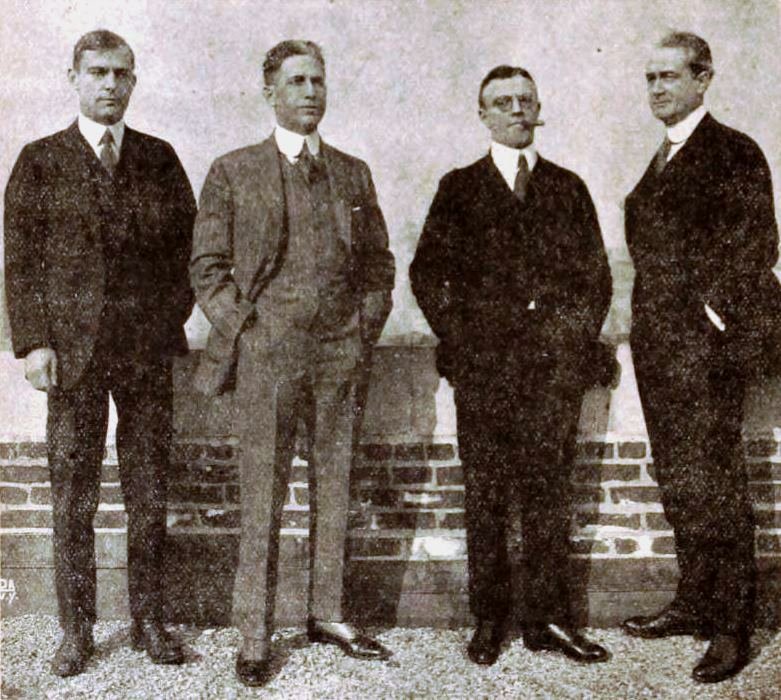 Four men in formal attire standing.