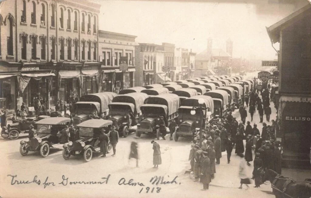 Historic street scene with trucks and people.