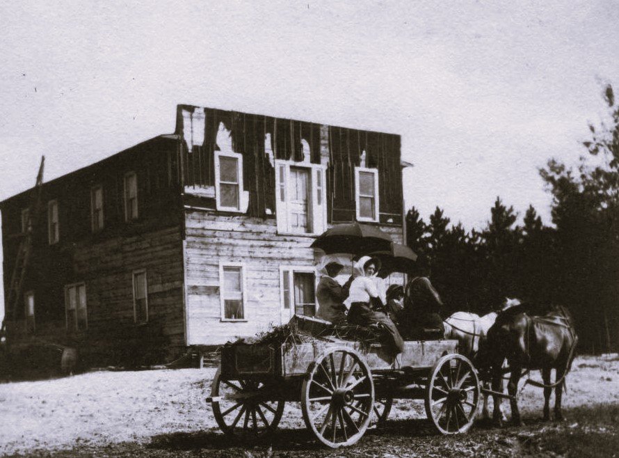Old wagon in front of farmhouse.